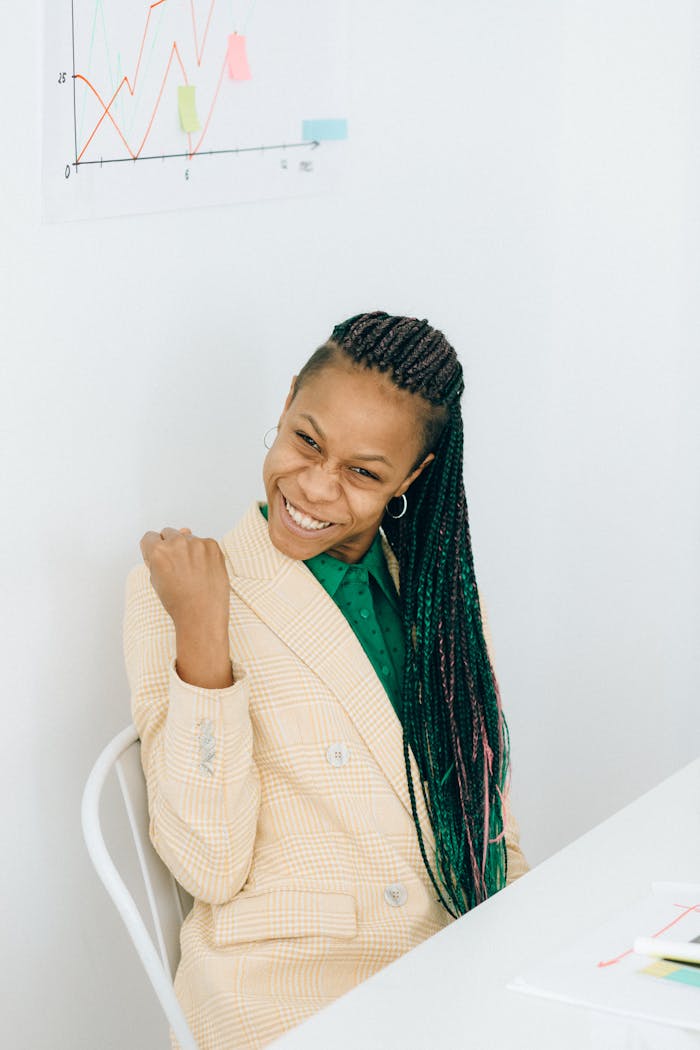 Smiling woman in business attire celebrating success indoors, displaying confidence.